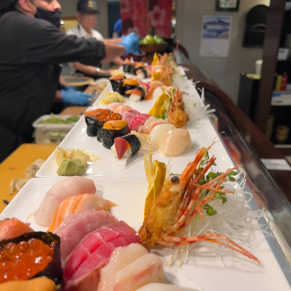 Sushi Chef preparing various sushi and sashimi platters at a sushi bar.