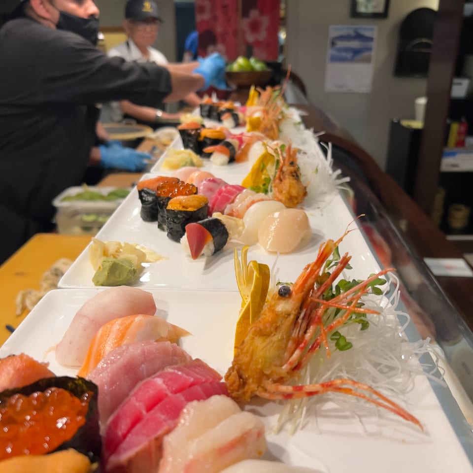 Sushi Chef preparing various sushi and sashimi platters at a sushi bar.