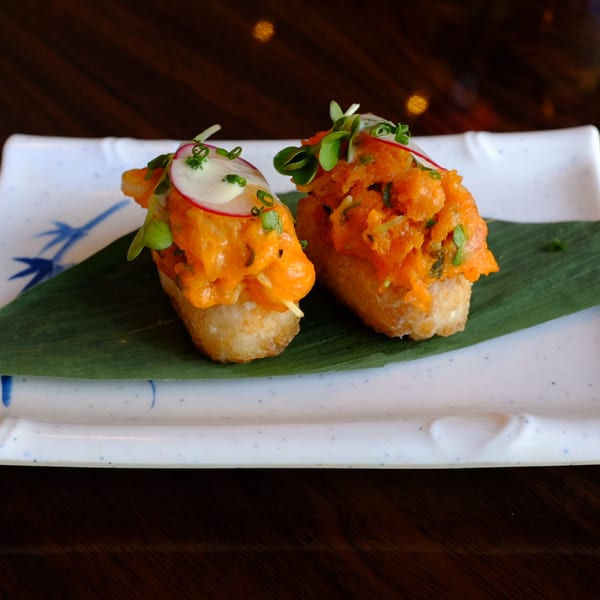 Two pieces of Sushi Chef's crispy rice sushi, topped with spicy salmon, radish, and microgreens.